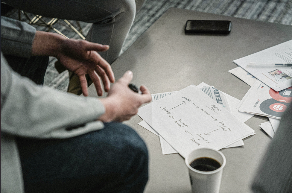 Close-up of a business meeting with papers, handwritten notes, and coffee on the table, representing financial strategy, planning, and decision-making.