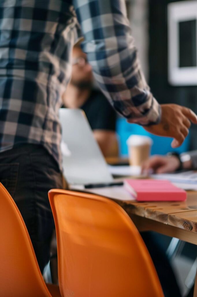 Business meeting scene with an orange chair, open laptop, and coffee cup, symbolizing creativity, collaboration, and innovation in financial and trust planning.